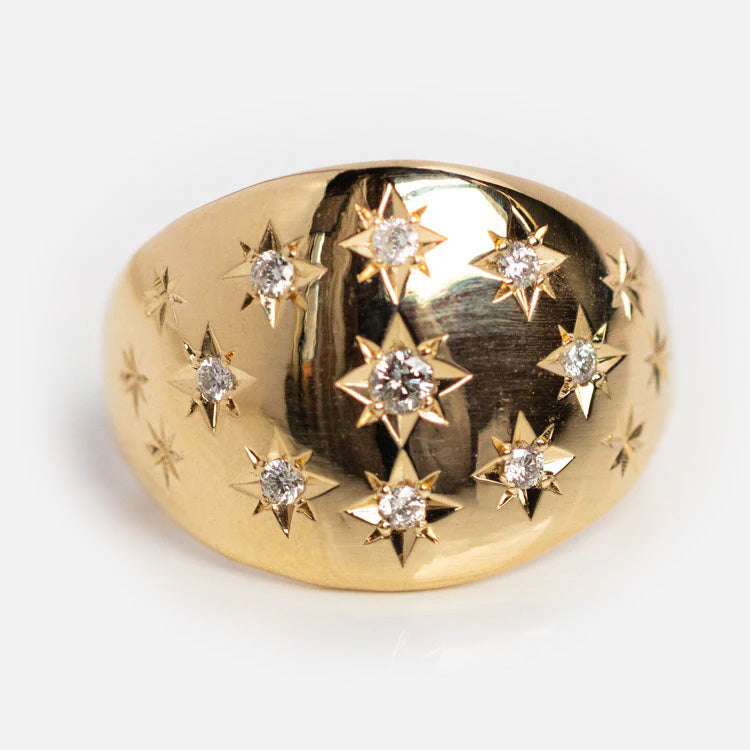 The Bombe Diamond Ring is crafted in 10k solid yellow gold and features star-shaped engravings with round diamonds at their centers, arranged in a scattered pattern—a stunning choice for any occasion.