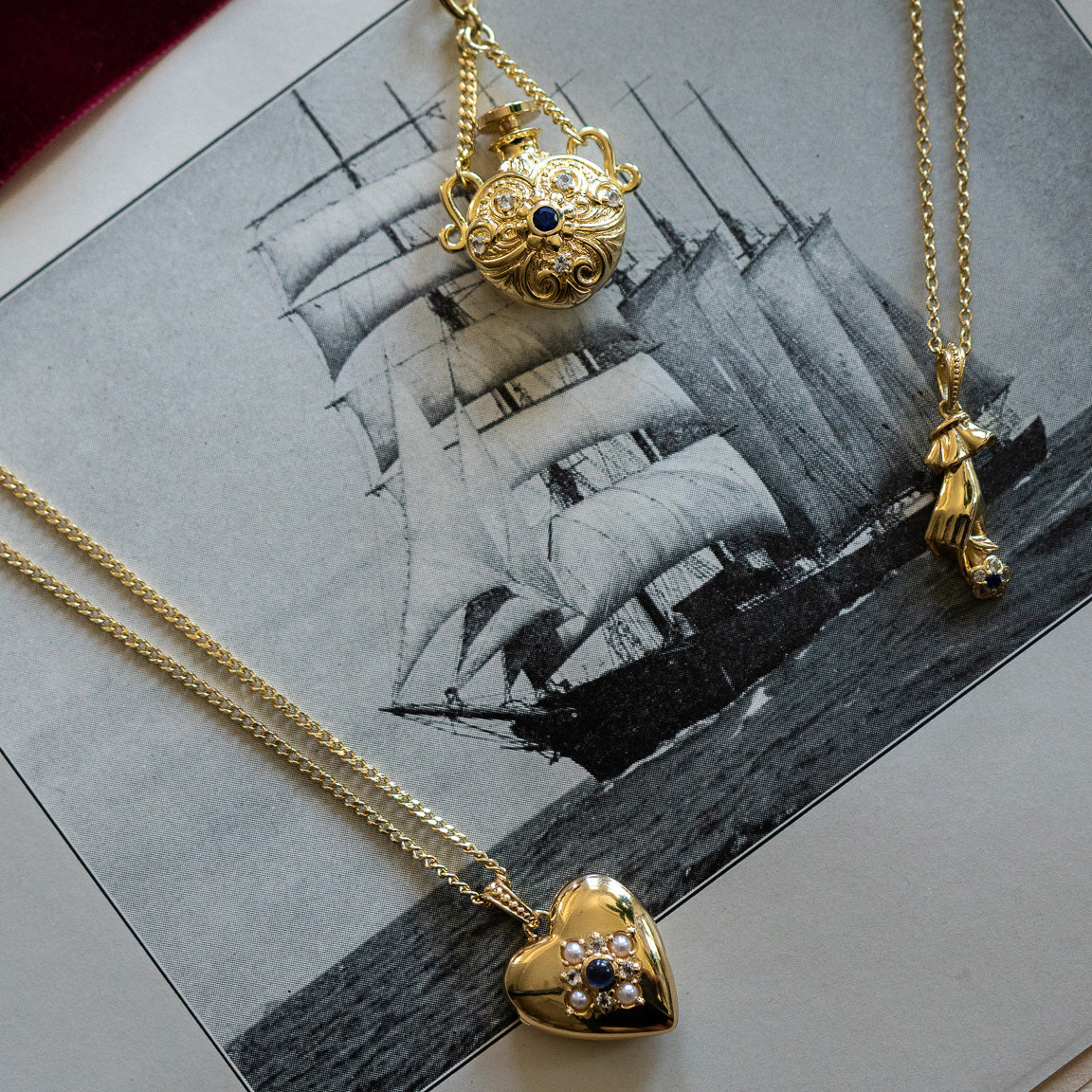 The Forget Me Not Blue Topaz Memento Necklace adds vintage-inspired charm to a black-and-white photograph of a grand sailing ship at sea.