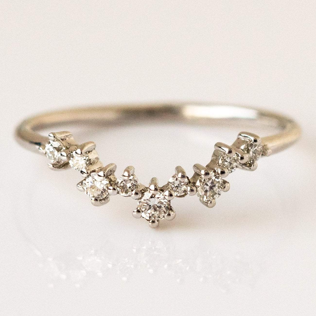 The Aster Diamond Cluster Band in White Gold (Sample Size 4) features a curved 14K white gold band set with seven ethically sourced round diamonds in a gentle arc, with the center stone slightly larger than the others.