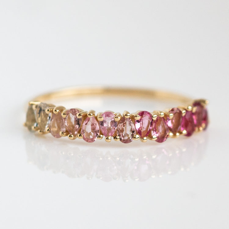 The Solid Gold Ombre Birthstone Ring Ruby Size 7 Sample features a row of oval rubies in ombre shades of pink, set in 9k solid yellow gold and displayed on a white reflective surface.