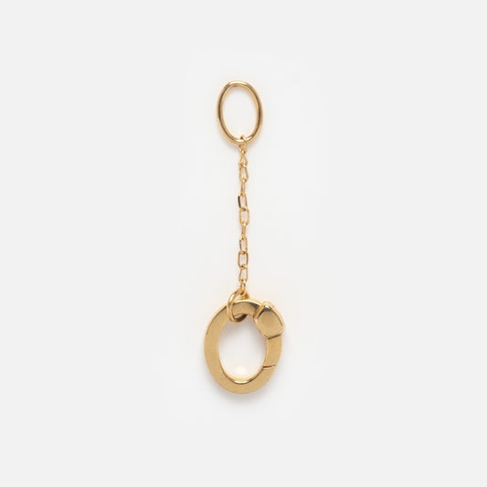 The Solid Gold Charm Clip features a small oval chain linked to a larger circular ring with a clasp—ideal as a keychain, bracelet attachment, or gold charm, shown on a plain white background.