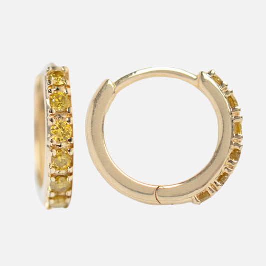 The Solid Gold Limited Edition Yellow Diamond Huggie Hoops feature small 10k yellow gold hoops, each with a row of round yellow diamonds on the front half, shown against a plain white background.