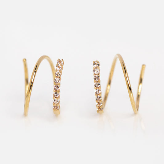 The Solid Gold Twist Double Piercing Huggies feature a row of sparkling clear stones on one side, ideal for double piercings, and are shown against a white background.