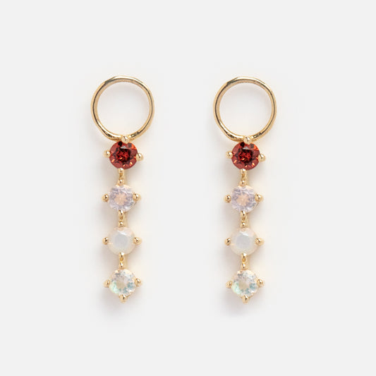 The Solid Gold Grow Acrostic Earring Charms feature gold hoops with a red gemstone at the top and three smaller light-colored gemstones hanging vertically, shown against a white background.