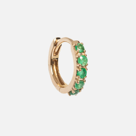 The Solid Gold Emerald Huggie Hoops are small gold earrings with five round natural emeralds set along the front, shown on a plain white background.