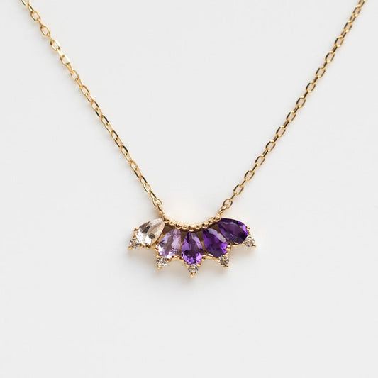 The Solid Gold Ombre Birthstone Necklace February Sample is a 9k yellow gold amethyst necklace with three purple gemstones, a white topaz, and sparkling accents in a fan design, shown on a white background.