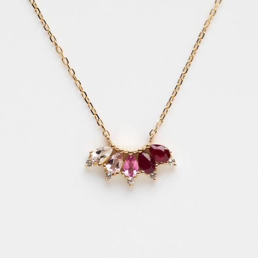 The Solid Gold Ombre Birthstone Necklace July Sample features a 9k yellow gold chain and a pendant with natural ruby, pink tourmaline, and clear stones arranged in a fan pattern against a white background.