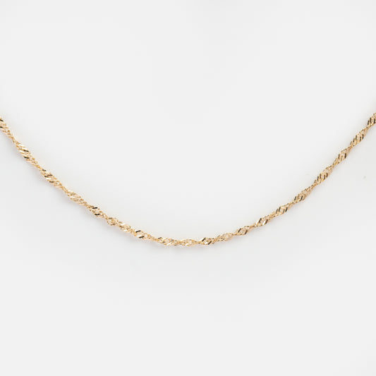 Gold chain necklace on a light gray background