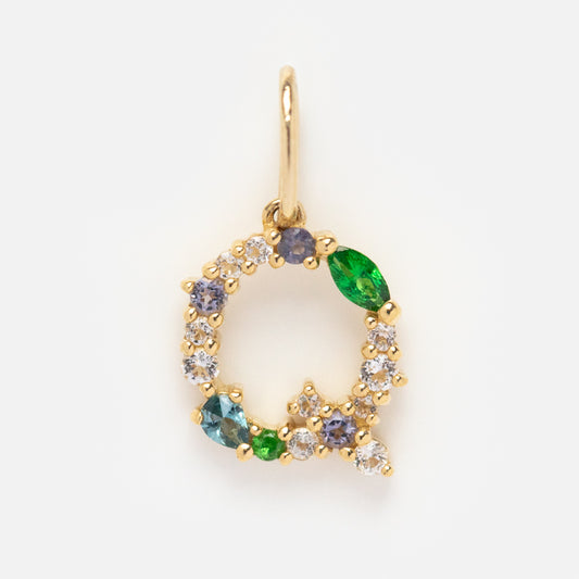 The Solid Gold Gemstone Letter Charm is a pendant shaped like the letter Q, featuring green, blue, and clear round gemstones, displayed on a plain white background.