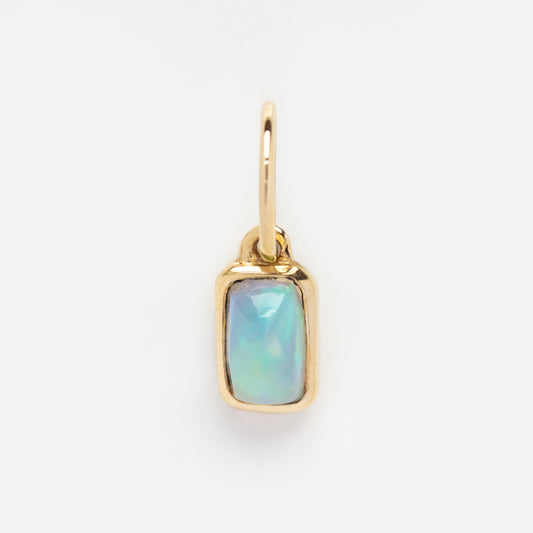 The Solid Gold Birthstone Baguette Charm features a rectangular opal baguette in a gold bezel, hanging from a small hoop and shown on a plain white background—ideal for personalized jewelry collections.