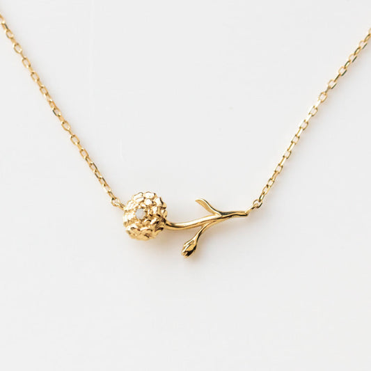 The Solid Gold Birth Flower Necklace October Sample features a delicate 9k yellow gold pendant shaped like a flower with textured petals and stem, inspired by natural opal, on a fine gold chain.
