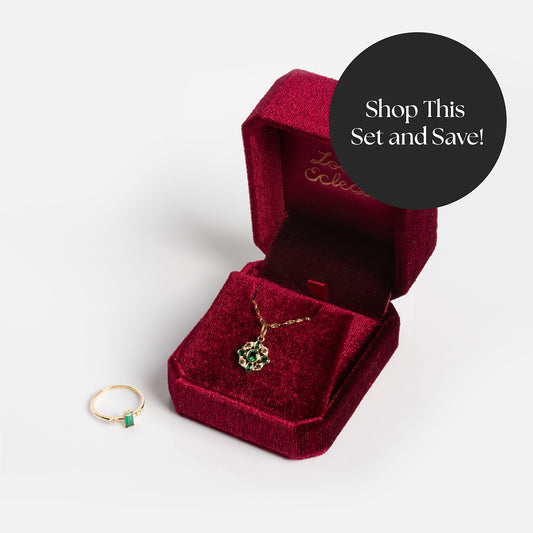The Solid Gold 2026 May Emerald Capsule Set with Free Gift is displayed—a gold ring and necklace, each with a green emerald. The necklace sits in a red velvet box. A black circle reads, Shop This Set and Save!.