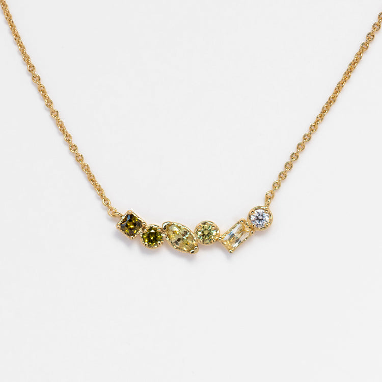 The Shades of You Ombre Birthstone Necklace features a delicate gold chain with seven assorted greenish-yellow gemstones set in a row, offering an elegant and personalized touch.
