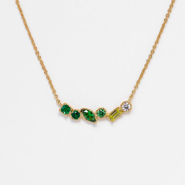The Shades of You Ombre Birthstone Necklace features five uniquely shaped green gemstones and a round white gemstone set in a minimalist gold row—an elegant, personalized piece ideal for standout style against a crisp white background.