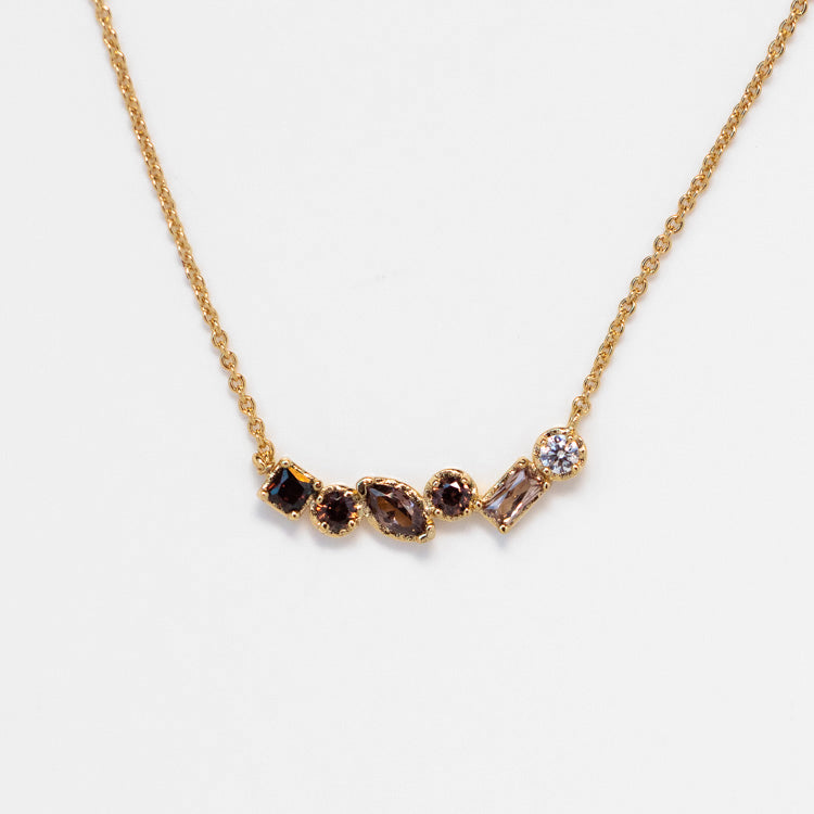 The Shades of You Ombre Birthstone Necklace features five assorted gemstones in various shapes—round, square, marquise, and rectangular—set in a row at the center for a personalized touch.