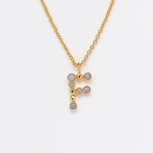 The Initial Charm Necklace Sample is a 14k yellow gold plated brass necklace featuring an F-shaped pendant with opalescent nano gems, shown against a white background.