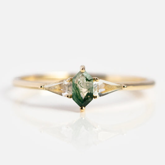 The Solid Gold Aquatic Agate Elements Hexagon Ring showcases a central hexagonal green gemstone, accented by two clear triangular stones, all set in solid gold and elegantly displayed on a white background.