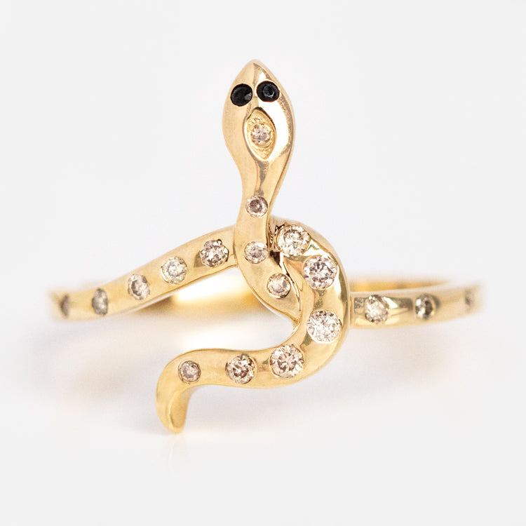 The Solid Gold Diamond Snake Ring for Protection is shaped like a coiled serpent, with small round diamonds along its body and head, and two black stones for eyes, set against a white background.