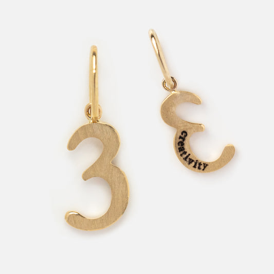 Two Solid Gold Number Charms shaped like the number three, each with a loop for attaching. One charm is engraved with “CREATIVITY” on the back, making them meaningful personalized jewelry or numerology gifts. Shown on a plain background.