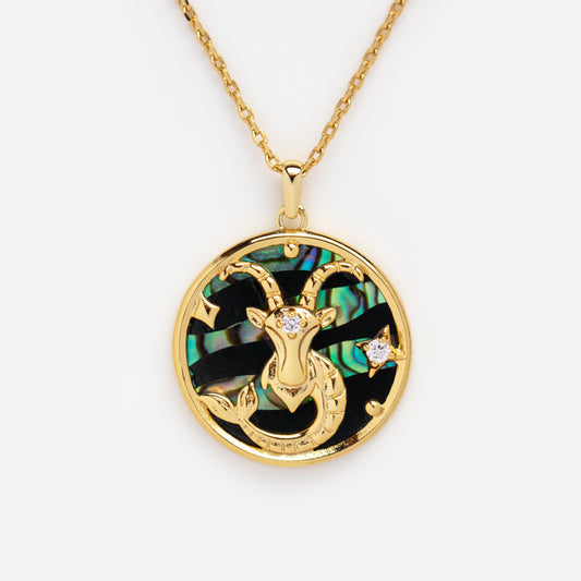 The Zodiac Pendant Necklace features a 14k gold plated Capricorn goat with sparkling stones on a green and black iridescent background, set on a fine gold chain.