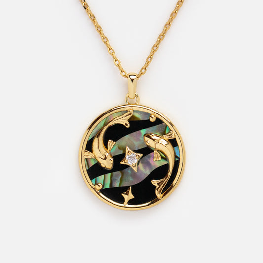 The Zodiac Pendant Necklace showcases two koi fish circling a star on abalone shell and black enamel, set in 14k gold plating and suspended from a gold chain.