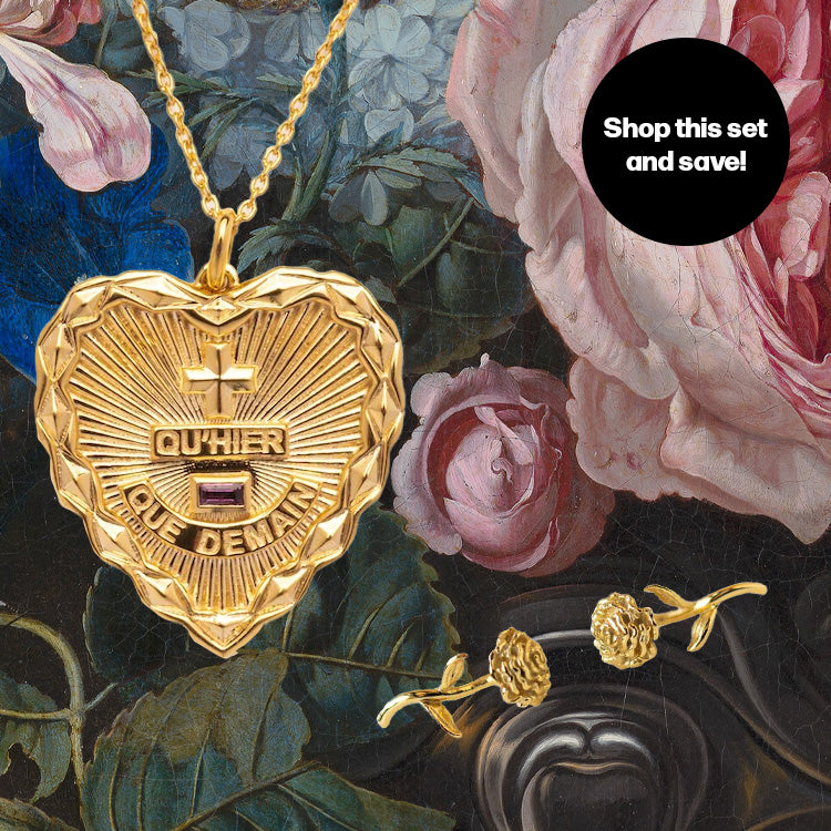 The Valentines Day Hearts and Flowers Gift Set features a gold heart pendant necklace with French text and birth flower earrings, displayed over painted roses. A black circle reads, Shop this set and save—perfect for Valentine’s gifting!.