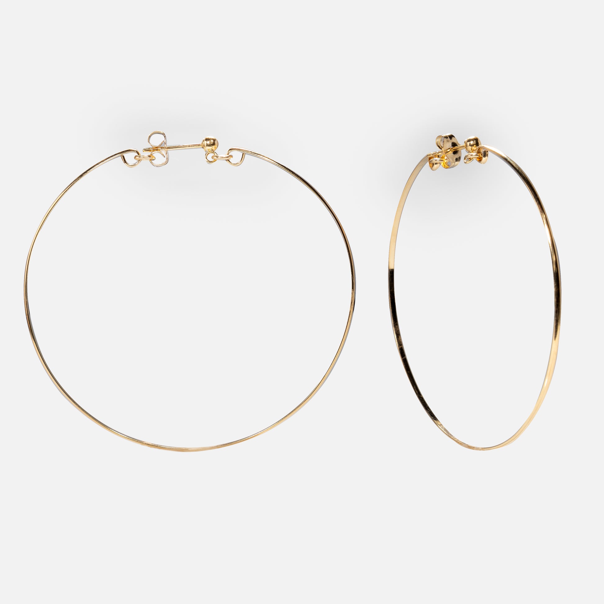 A pair of Valour Hoops—lightweight gold filled earrings with clasp fastenings—shown on a plain white background, one lying flat and the other standing upright.
