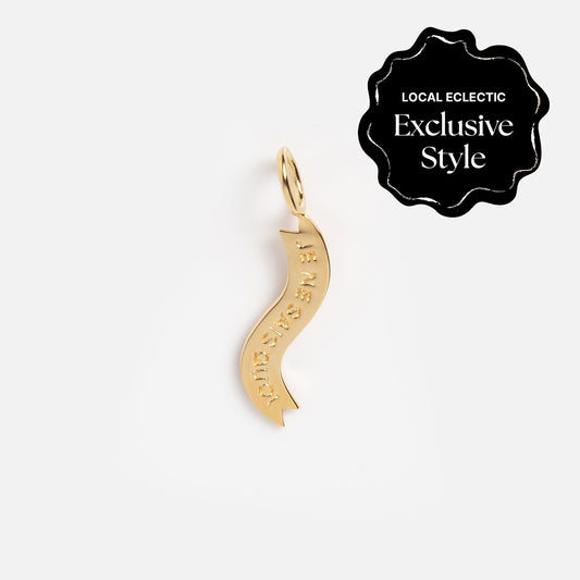 A wavy, gold-plated pendant from Charms by I Like It Here Club features engraved text and is displayed on a white background. The top right black label reads "Local Eclectic Exclusive Style"—a playful piece for personalized charms.