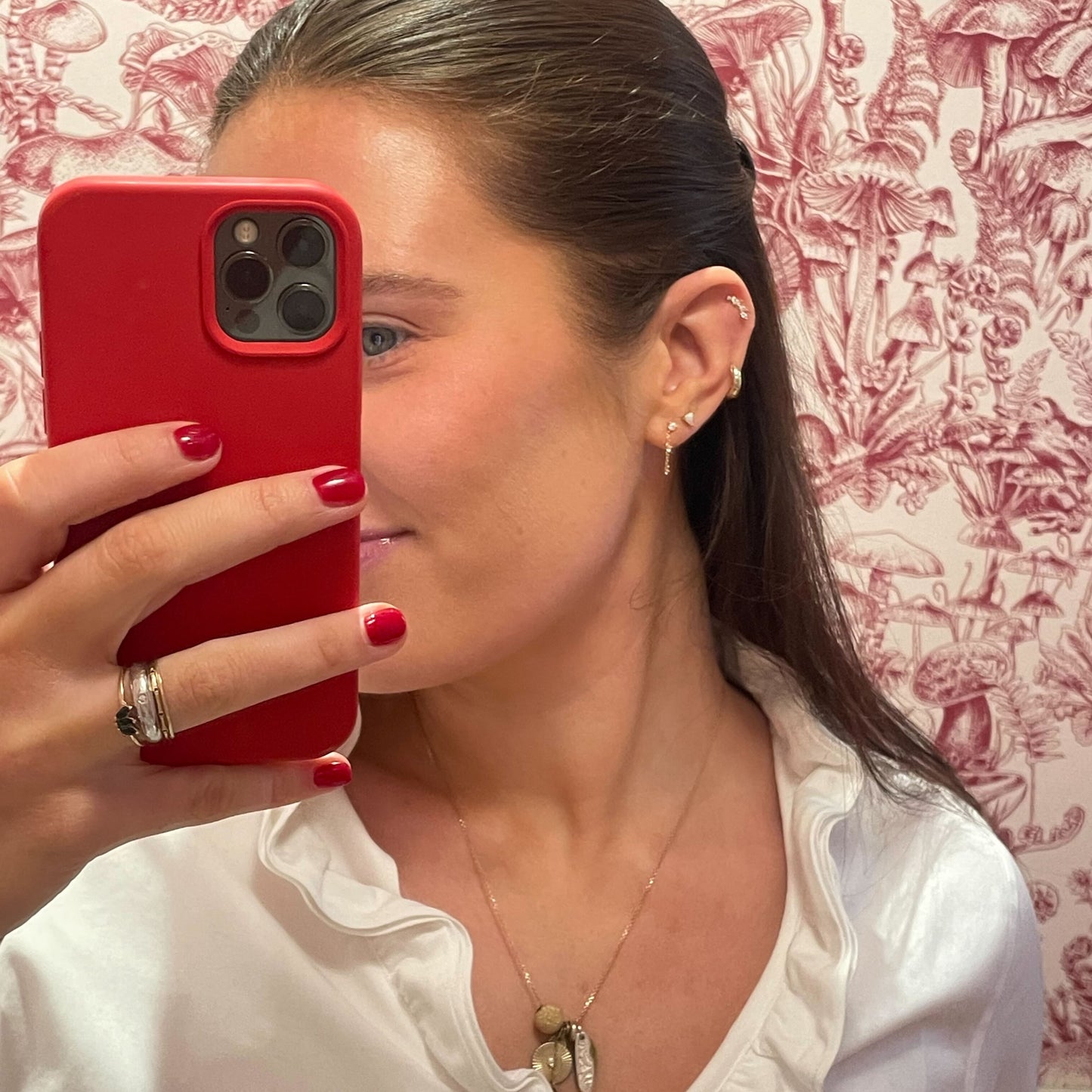 Person holding a red phone with a patterned wall in the background wearing the Classic Birthstone Earring Set 