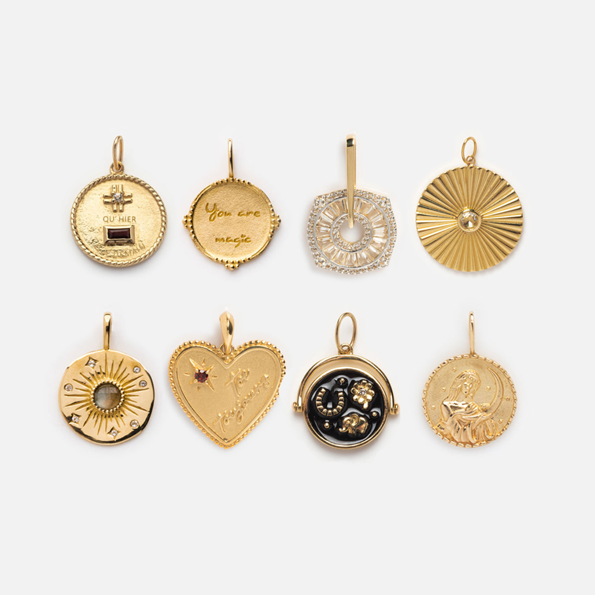 Eight Local Eclectic exclusive Solid Gold Coin Charms in various shapes—including circular, heart, and geometric—are displayed in two rows, some featuring engravings, gemstones, or decorations for uniquely personalized jewelry.
