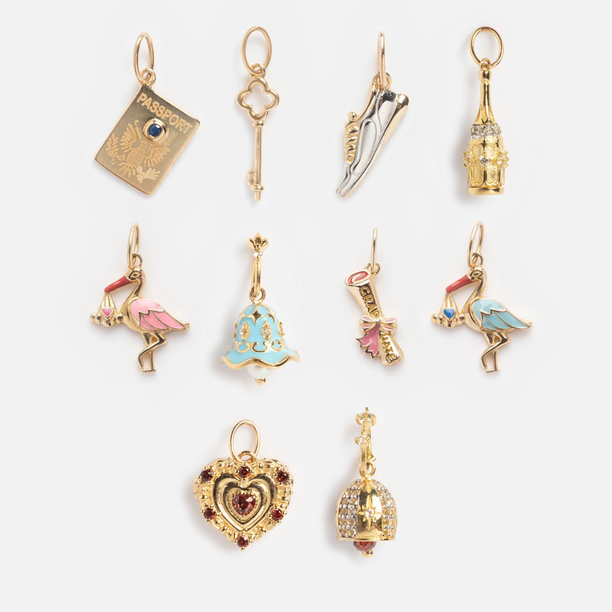Ten Solid Gold Celebration Charms, including a passport, ballet shoes, flamingos with hats, and a heart locket, are displayed on a white background—perfect for marking special memories.