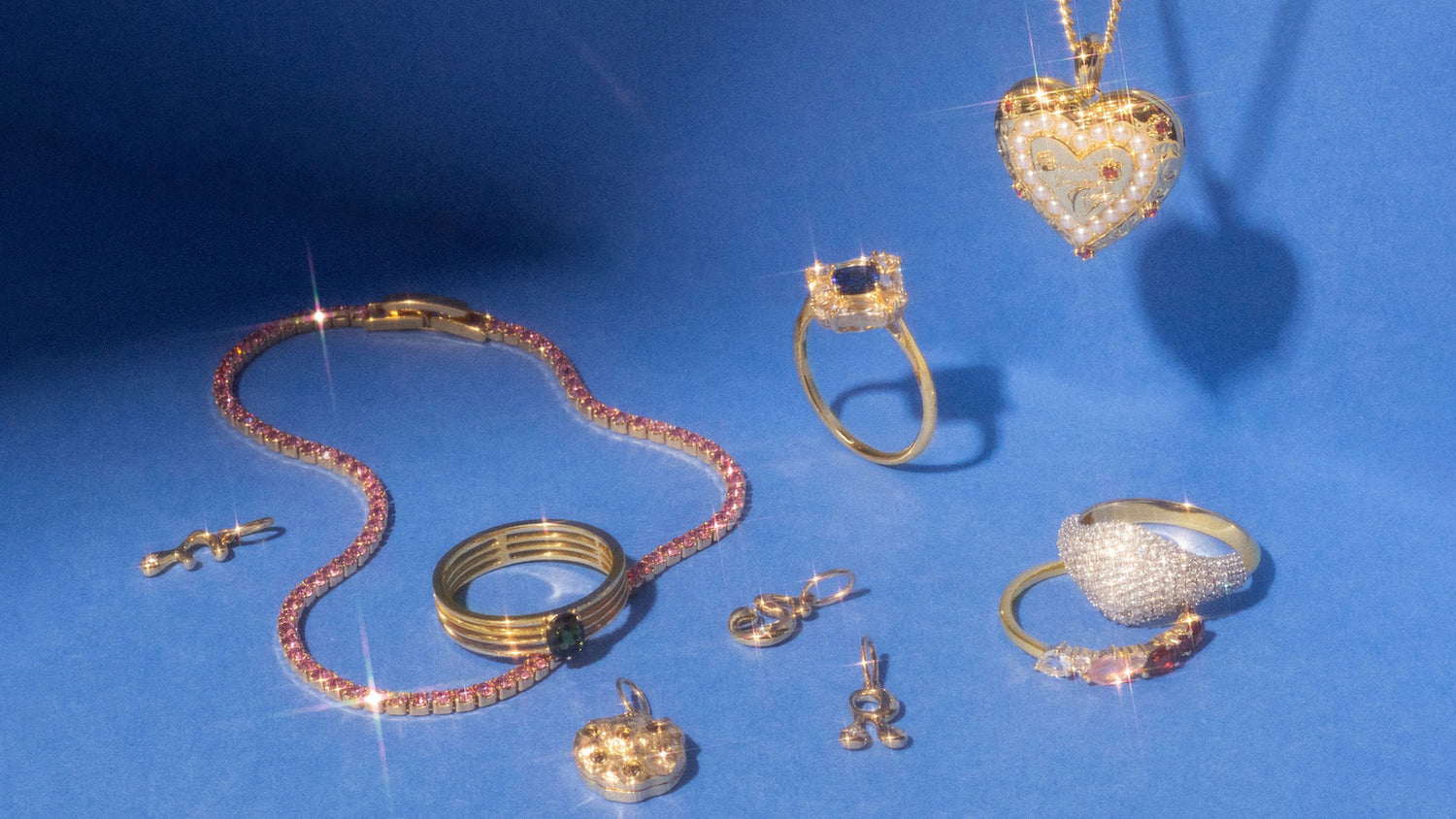 Collection of gold jewelry including rings, a necklace, and pendants on a blue background