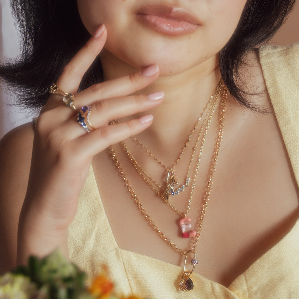 Close-up of a woman wearing multiple necklaces and rings with a blurred background