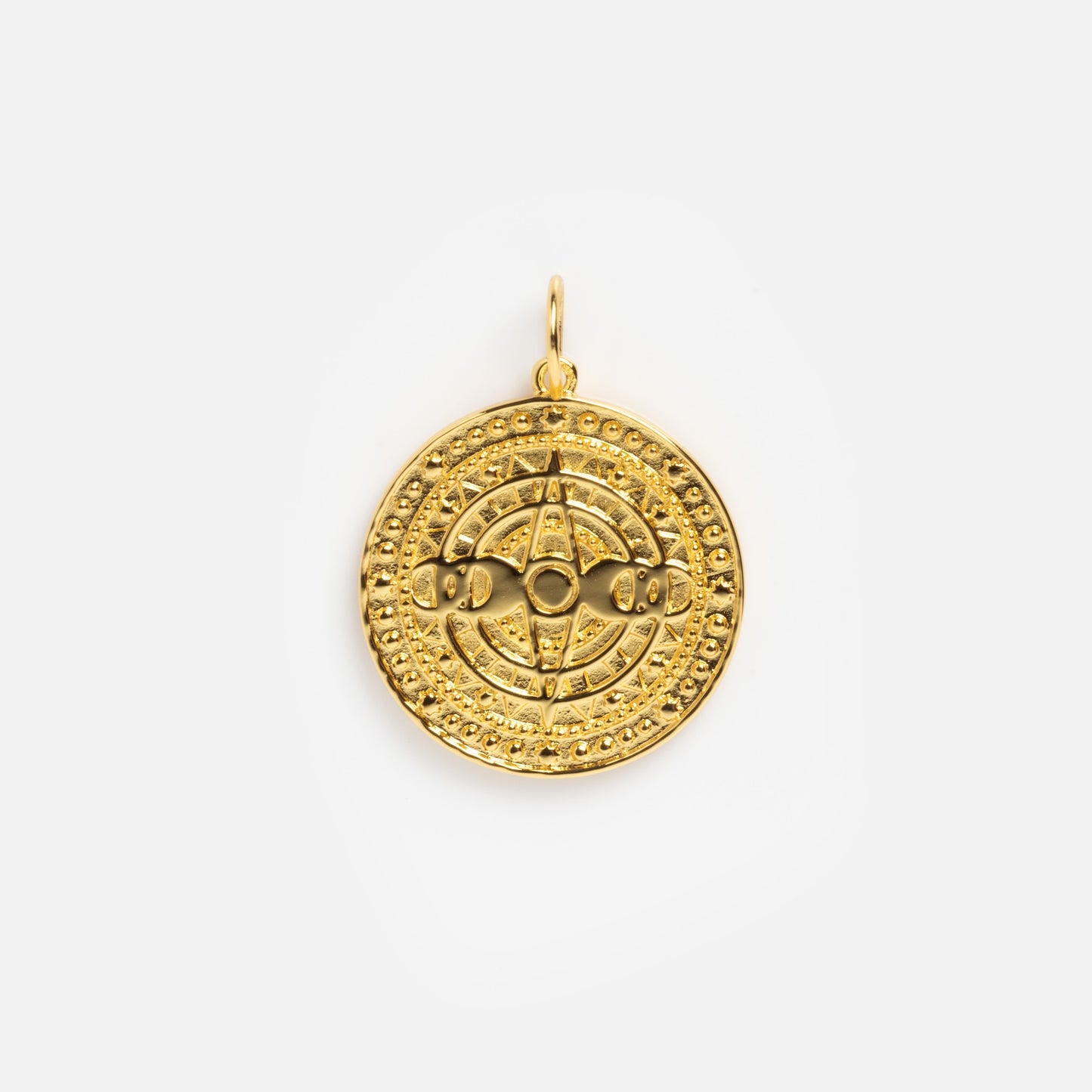 The Charms by Jurate JLA is a round yellow gold plated pendant with raised geometric and circular patterns, a small top loop for attaching to a chain, and is ideal for layering with other charms.