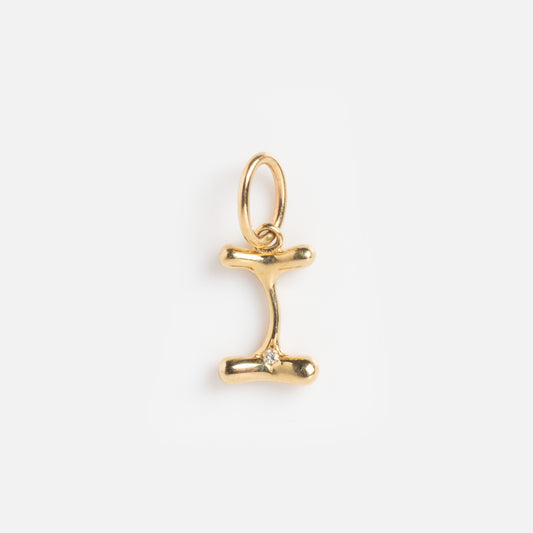 The Solid Gold Organic Monogram Charm Sample is a gold pendant shaped like a capital letter I with rounded edges and a small clear gemstone in the center, displayed on a plain white background.