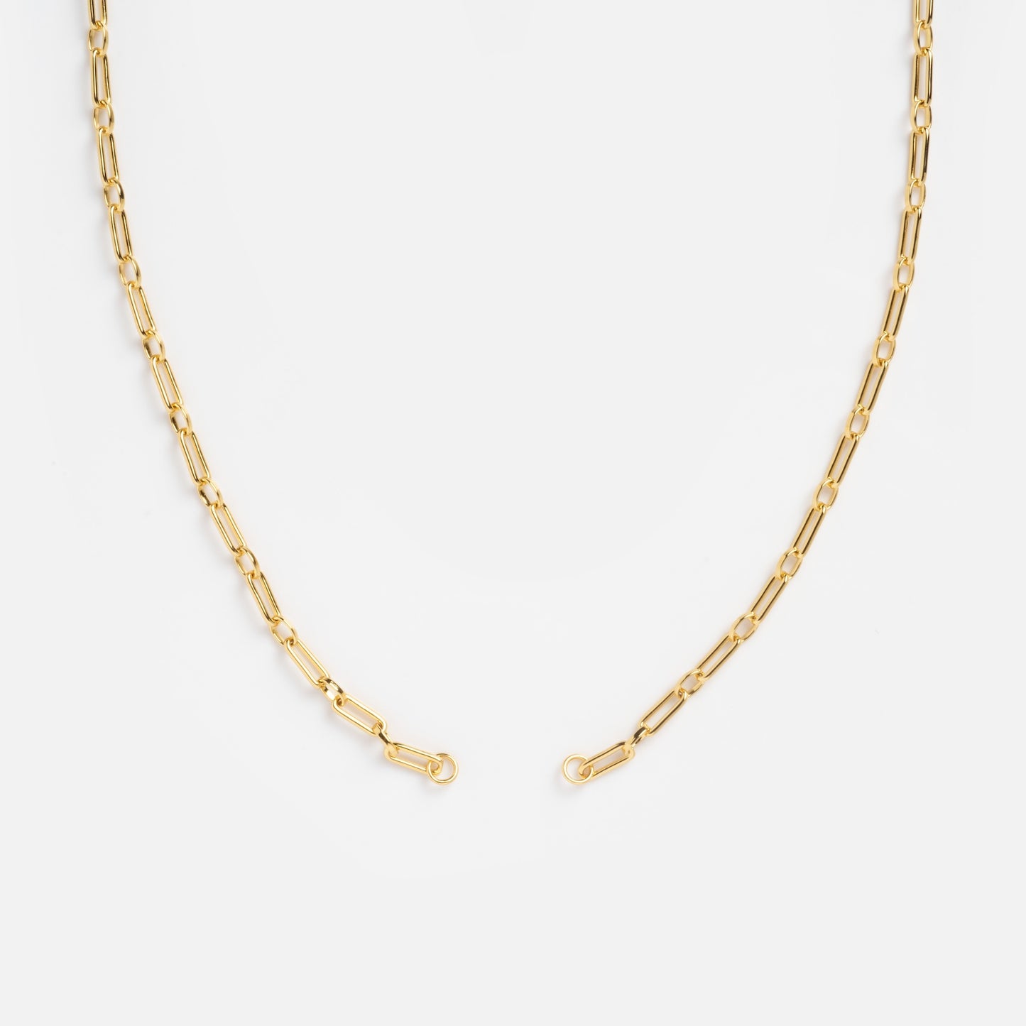 The Perfect Start Charm Holder Necklace features delicate gold-plated elongated oval links, arranged in a semi-circle on a white background—ideal as a customizable jewelry piece or versatile charm holder.