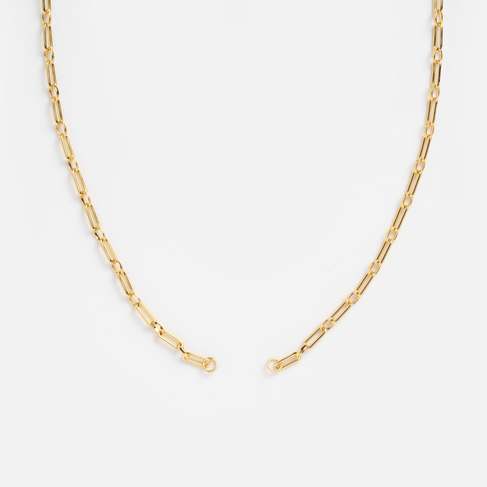 The Perfect Start Charm Holder Necklace features delicate gold-plated elongated oval links, arranged in a semi-circle on a white background—ideal as a customizable jewelry piece or versatile charm holder.