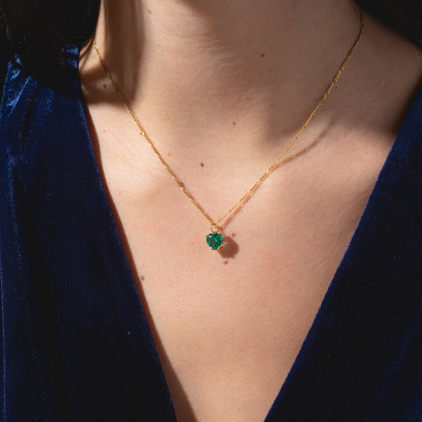 A person wearing the One of a Kind 14k Lab Emerald Heart Charm necklace.