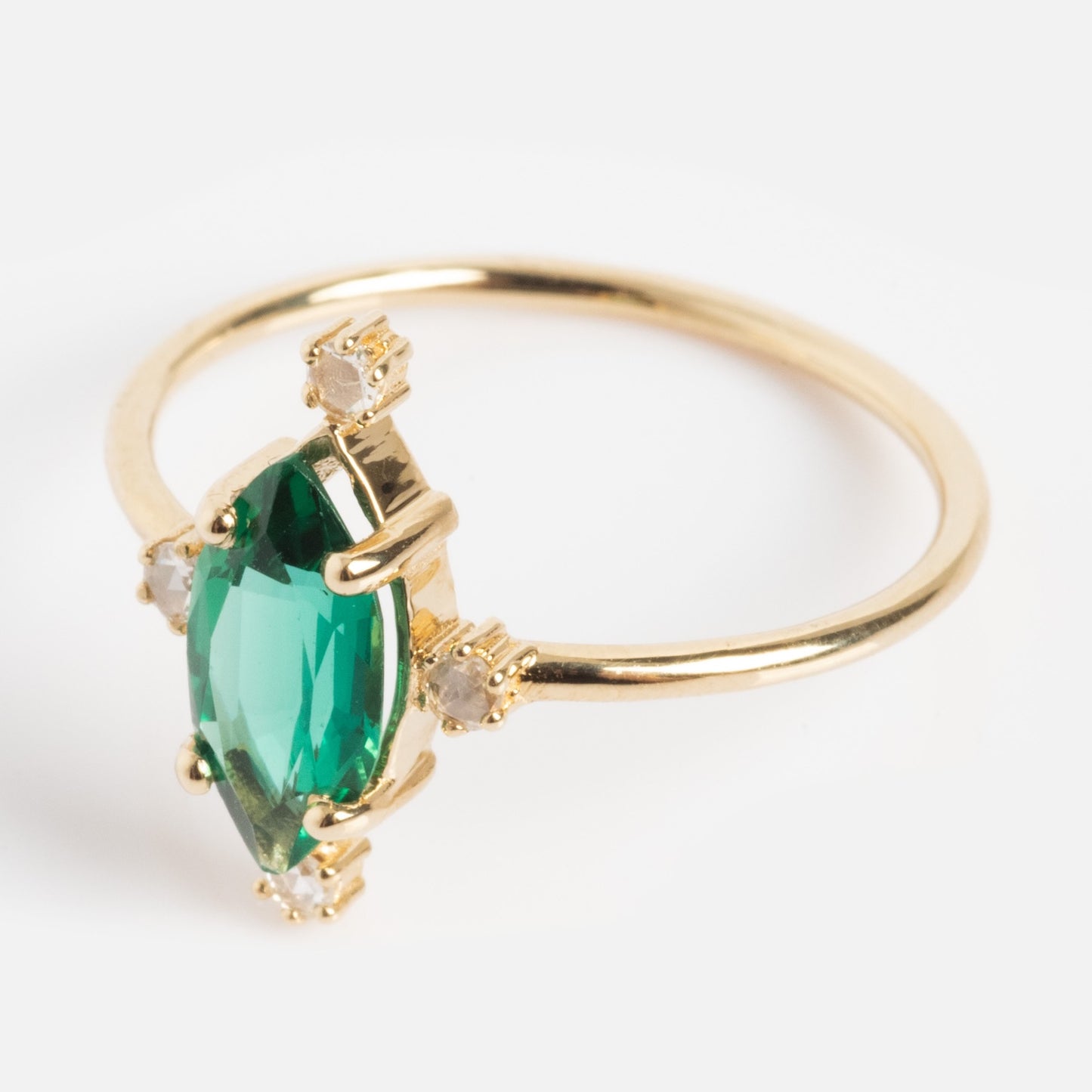 The One of a Kind 14k Marquis Lab Emerald and Diamond Ring features a marquise-cut lab emerald center with four round diamonds at each corner, beautifully showcased on a white background.