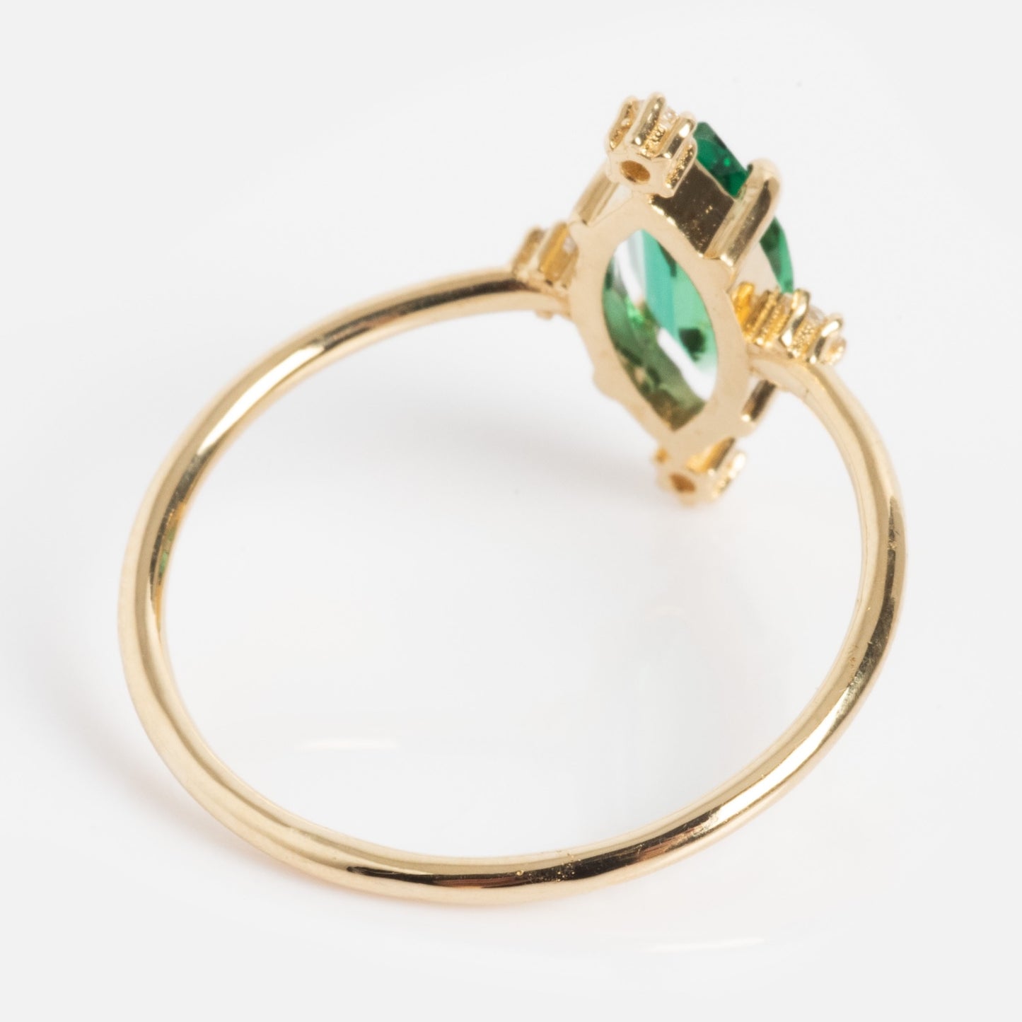 The One of a Kind 14k Marquis Lab Emerald and Diamond Ring features a marquise-cut green lab emerald in a raised four-prong setting, displayed at an angle on a white background.