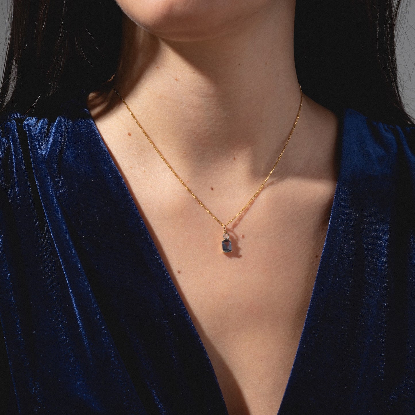 A woman wears a deep blue velvet top and the One of a Kind 14k Lab Alexandrite and Diamond Charm necklace. The focus is on her neck and chest, with her face partially out of frame.
