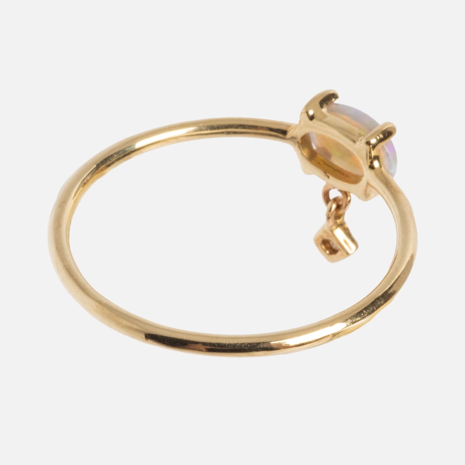 The One of a Kind 14k Sweetest Opal with Diamond Dangle Ring features a round opal in a prong setting and a sparkling diamond charm hanging from the band.