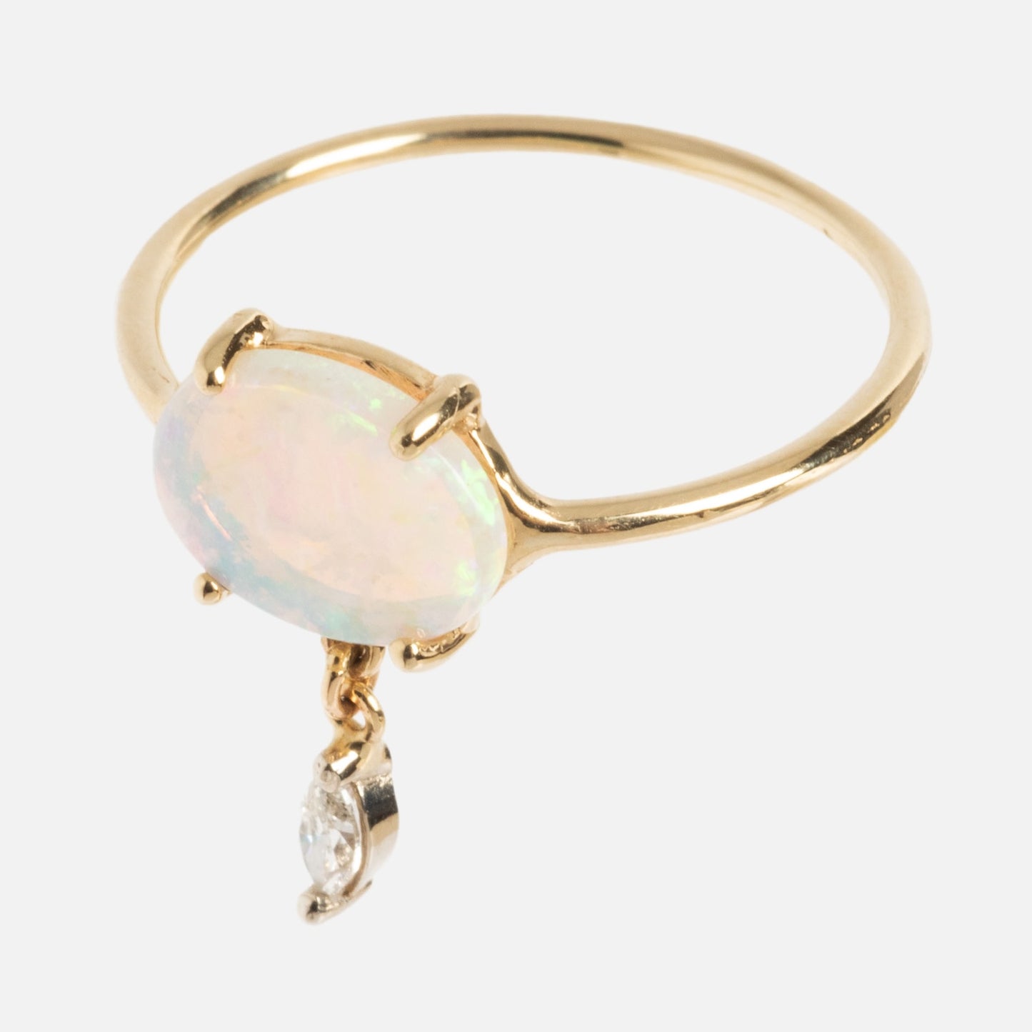 The One of a Kind 14k Opal with Diamond Dangle Ring features an oval opal in a prong setting, accented by a marquise-cut diamond dangle below the gemstone.