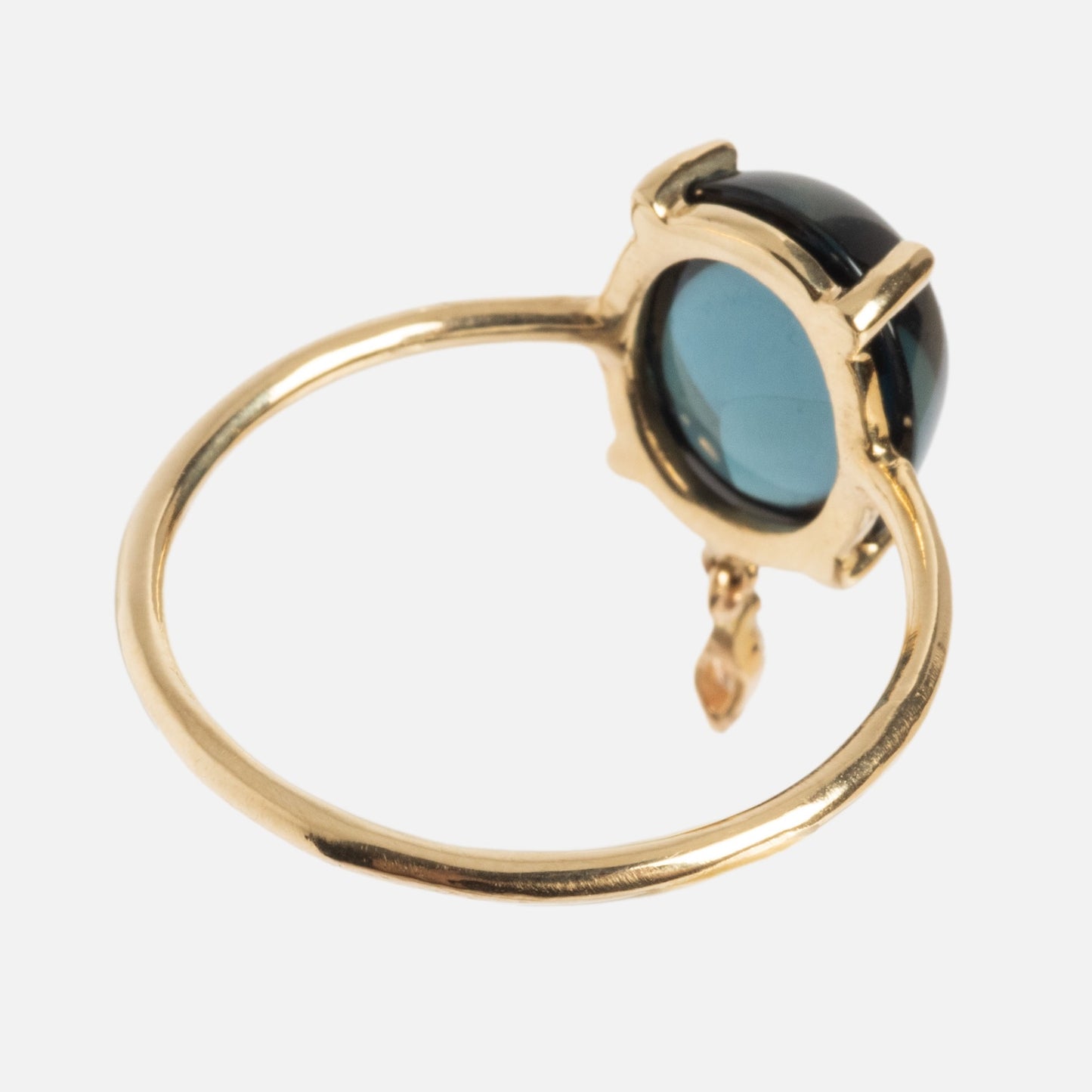 The One of a Kind 14k London Blue Topaz with Diamond Dangle Ring features a round dark blue gemstone in a raised bezel and a small diamond dangle charm, beautifully displayed on a white background.