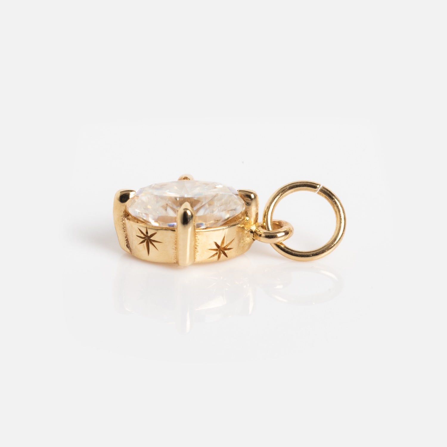 A One of a Kind 14k gold oval Moissanite charm with hand-engraved details and an attached circular bail, shown on a white background.