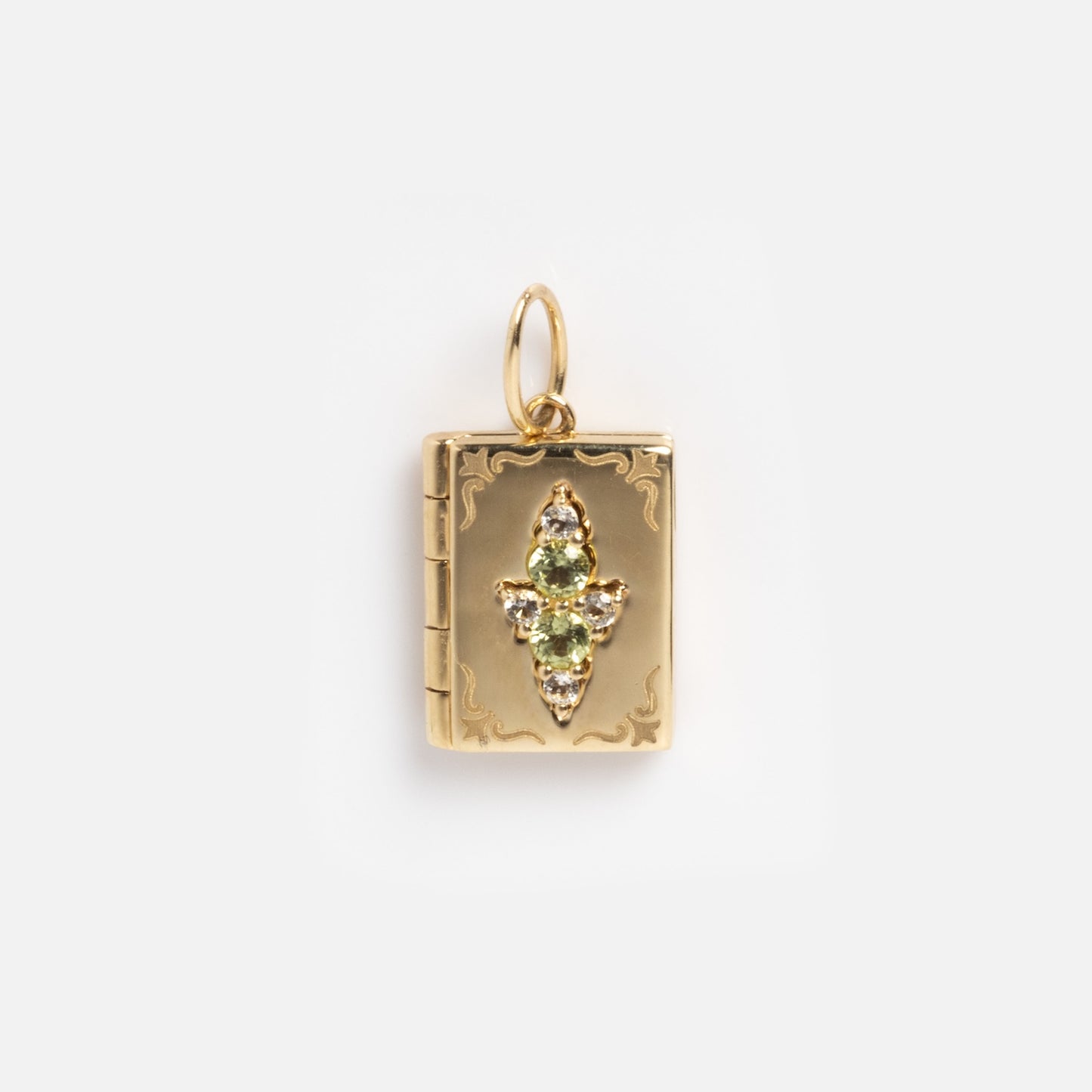 A Local Eclectic exclusive, the Solid Gold Amulet Charm features an ornate, book-shaped design with three vertical green gemstones and a small loop, perfect for adding to your favorite gemstone charm necklace.
