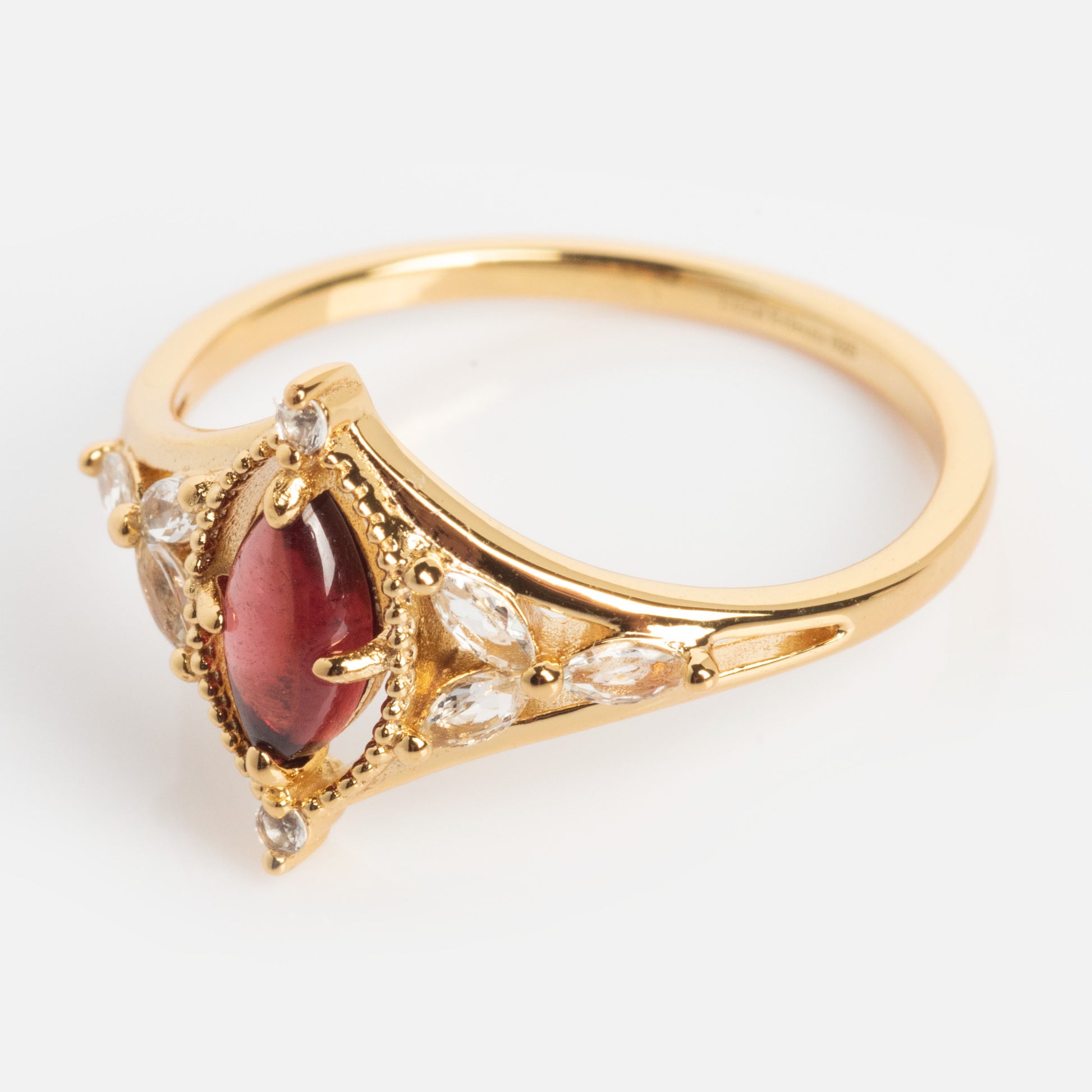 The 2026 January Capsule Art Deco Garnet Ring features a marquise red garnet center, accented by clear marquise and round stones in yellow gold vermeil, shown on a white background.