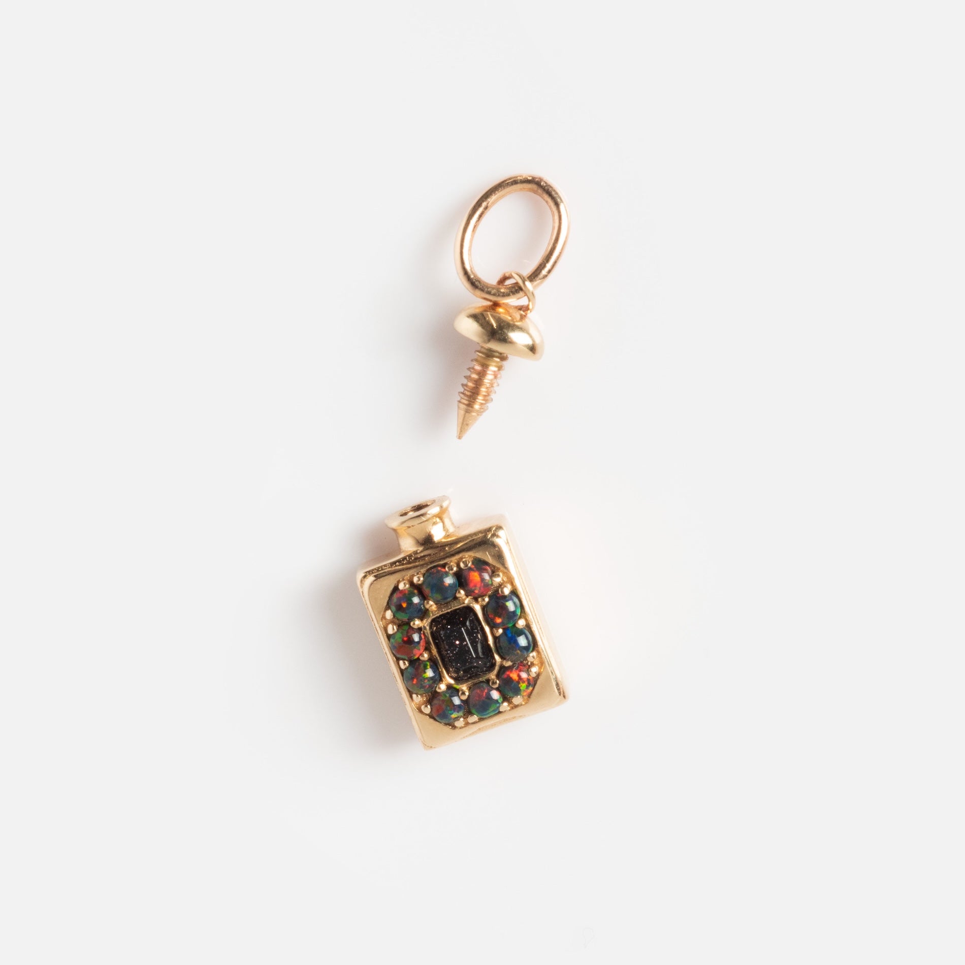 The Solid Gold Amulet Charm is a small flask-shaped piece with a screw-on cap, colorful gemstones surrounding a central dark stone, shown on a white background—a Local Eclectic exclusive.