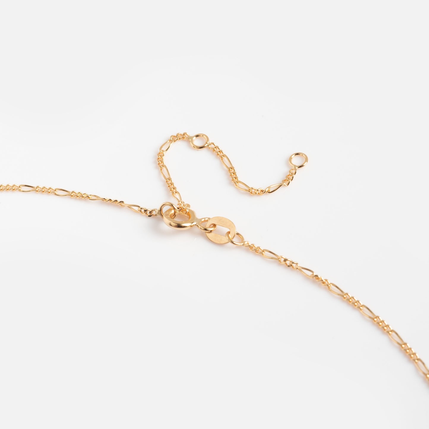 The Solid Gold Figaro Chain is a 9k yellow gold necklace featuring a lobster clasp and adjustable links, ideal for layering. Shown on a plain white background.