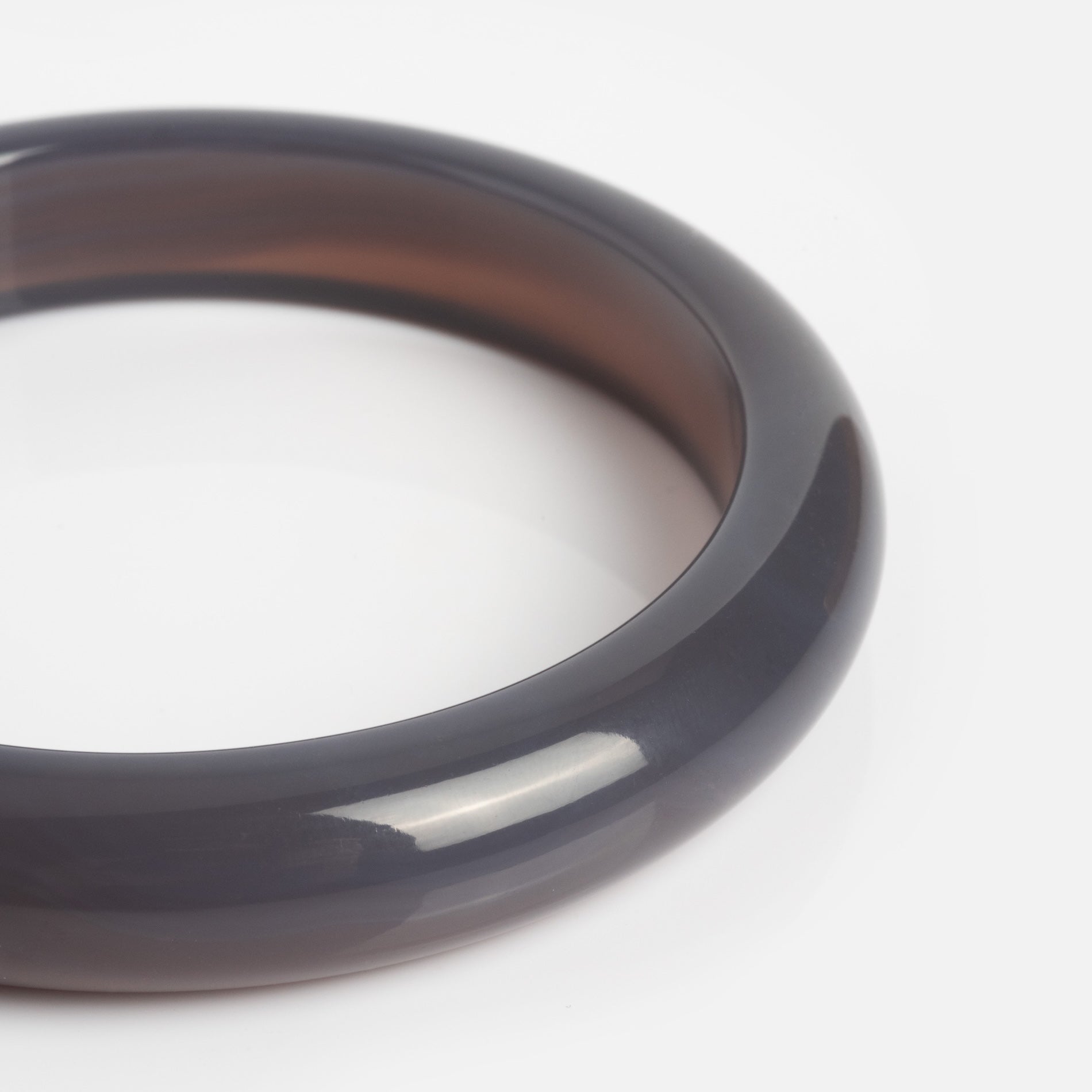 A smooth, polished Moon Purple Chalcedony Stone Bangle with a glossy dark gray finish is displayed against a plain white background.